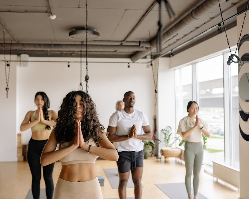 A multicultural group of adults practicing yoga poses together in a bright studio