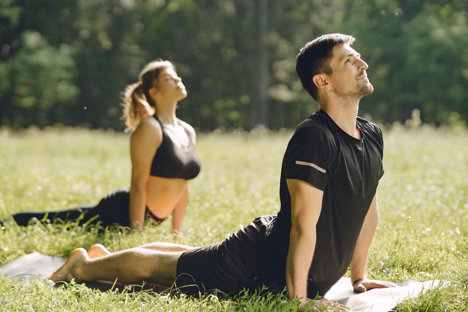 Man and woman stretching in an outdoor yoga session in a sunny field