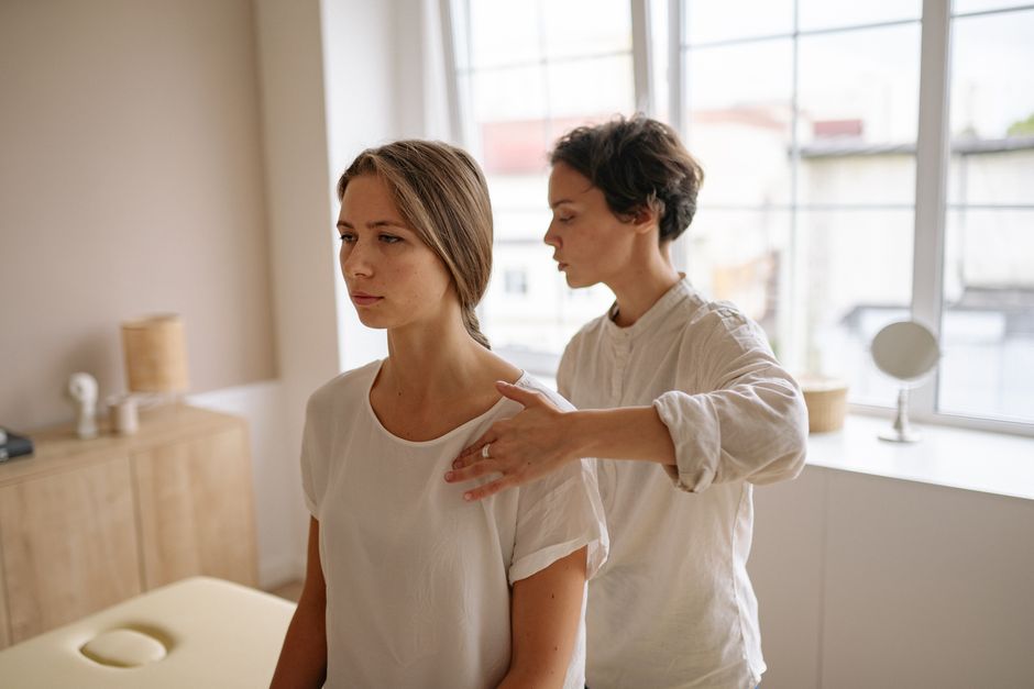 A woman receives shoulder therapy from a therapist in a serene room with natural light